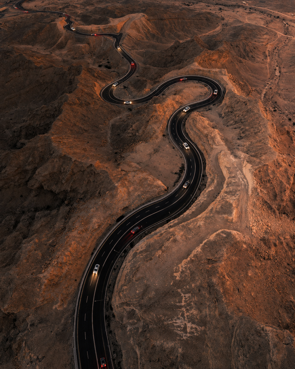 Cars traveling on a winding mountain road seen from above
